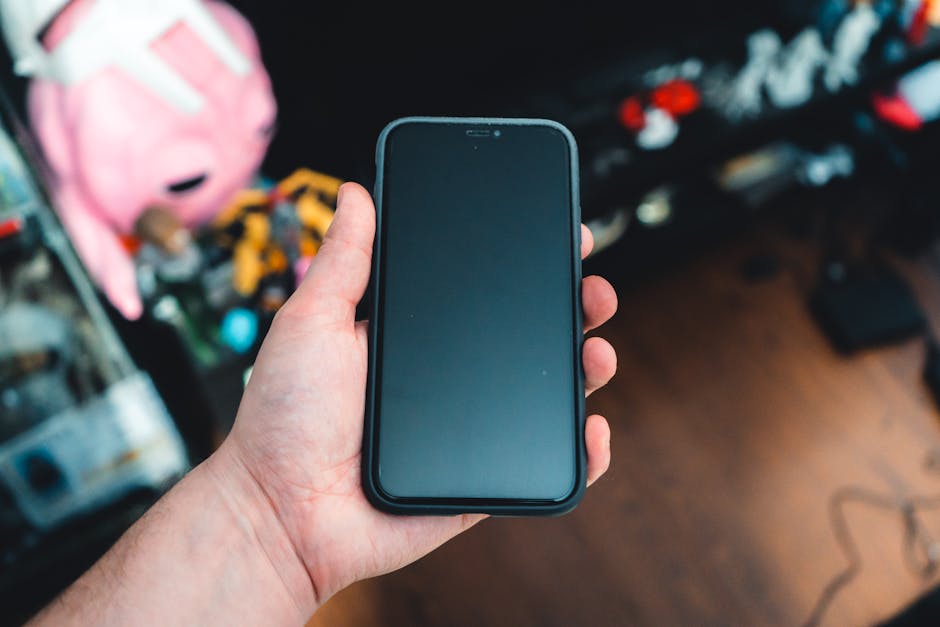 A hand holding a smartphone in a cozy indoor environment with a blurred background.