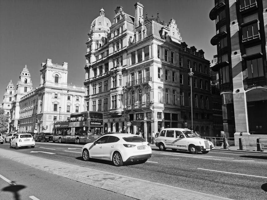 Black and white image of iconic London street with classic architecture and traffic, captured in daylight.