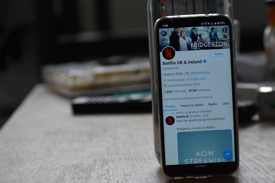 Smartphone showing Netflix's Twitter page on a wooden table.
